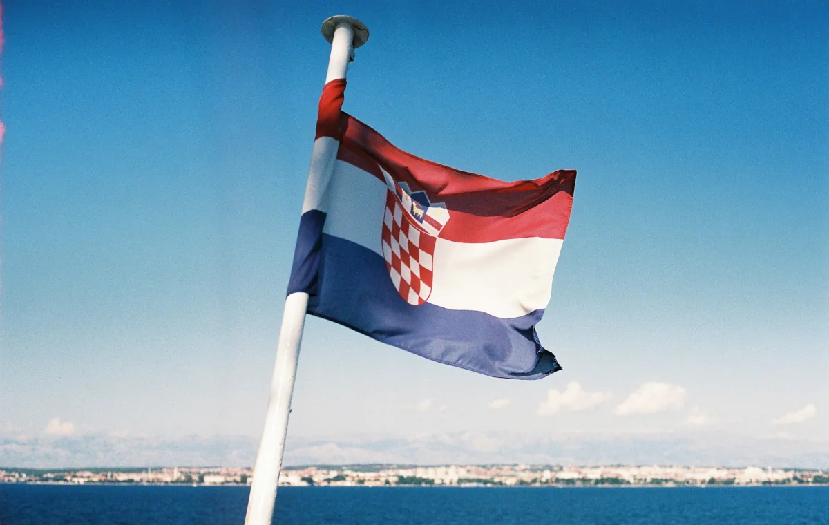 Croatian flag on a ferry crossing the Adriatic, with the Dalmatian coastline visible in the background